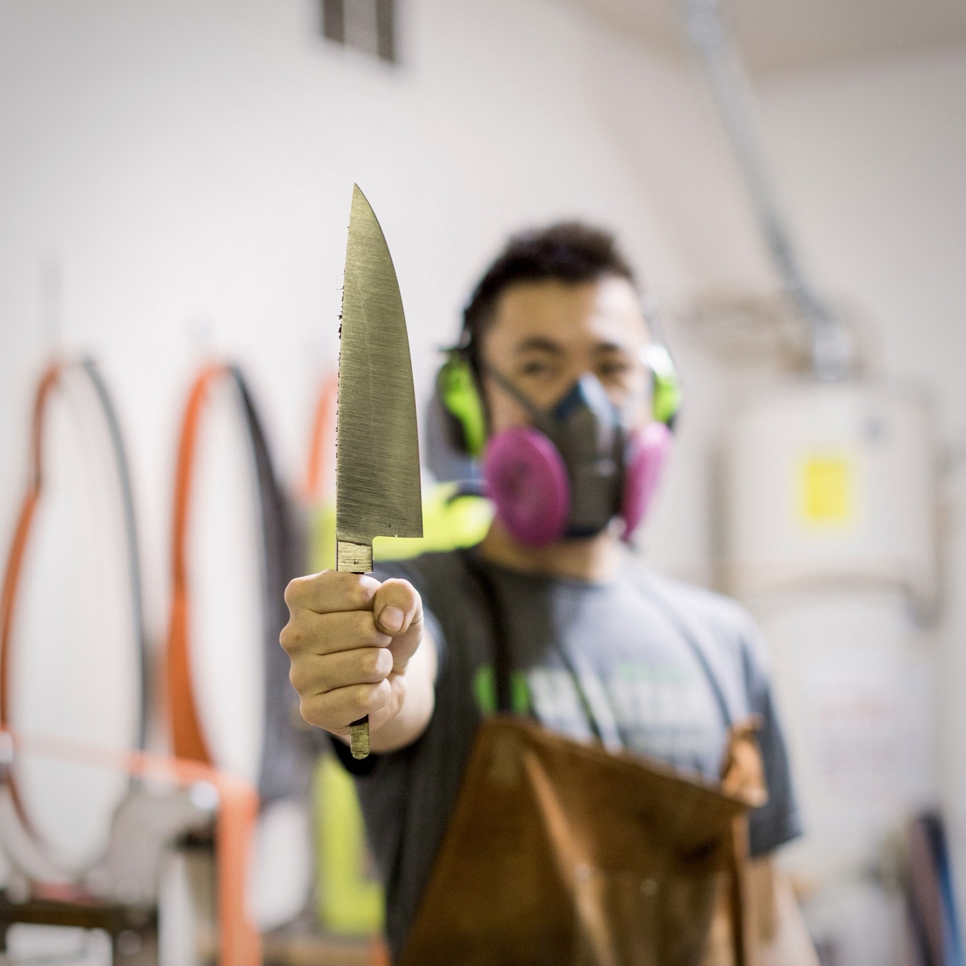 Jesse Hu in the shop holding a finished chef's knife